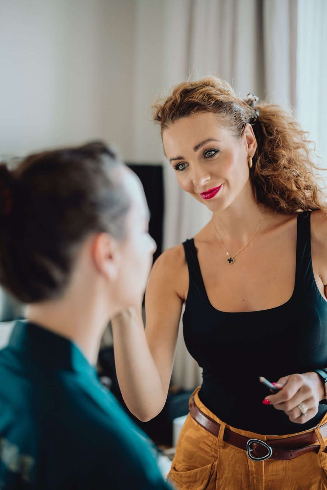 Nikoleta smiling at a client while applying makeup