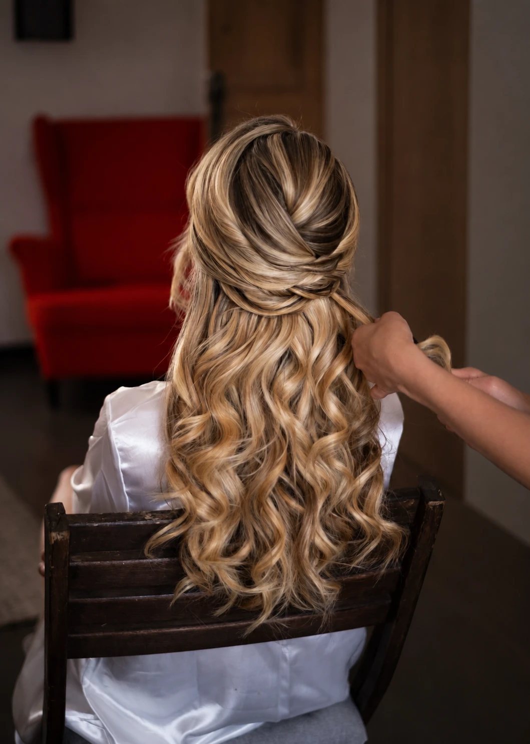 Artist shaping half-up Hollywood waves on a bride, seen from behind