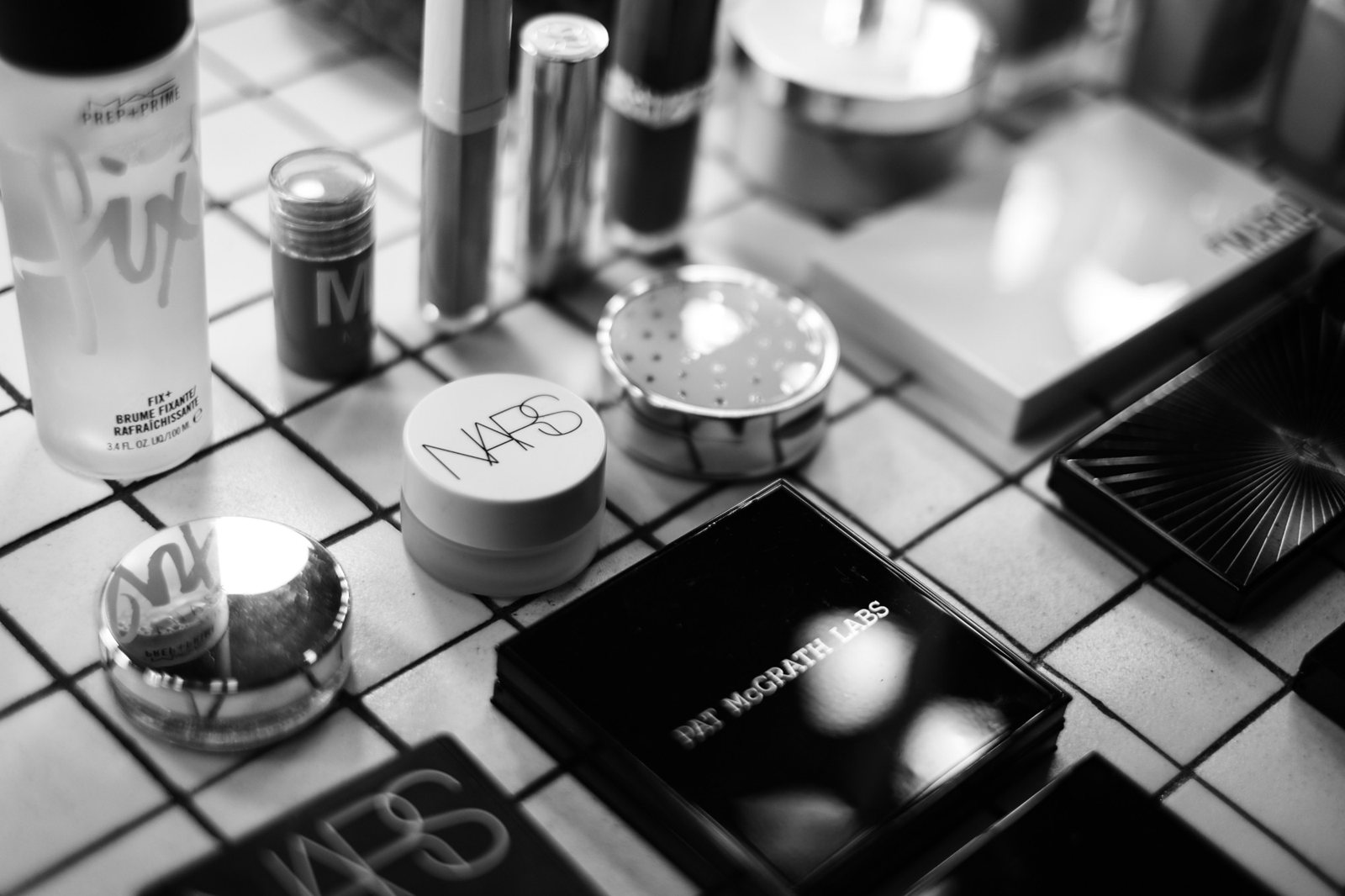 Professional makeup products laid out on a tiled table, black and white